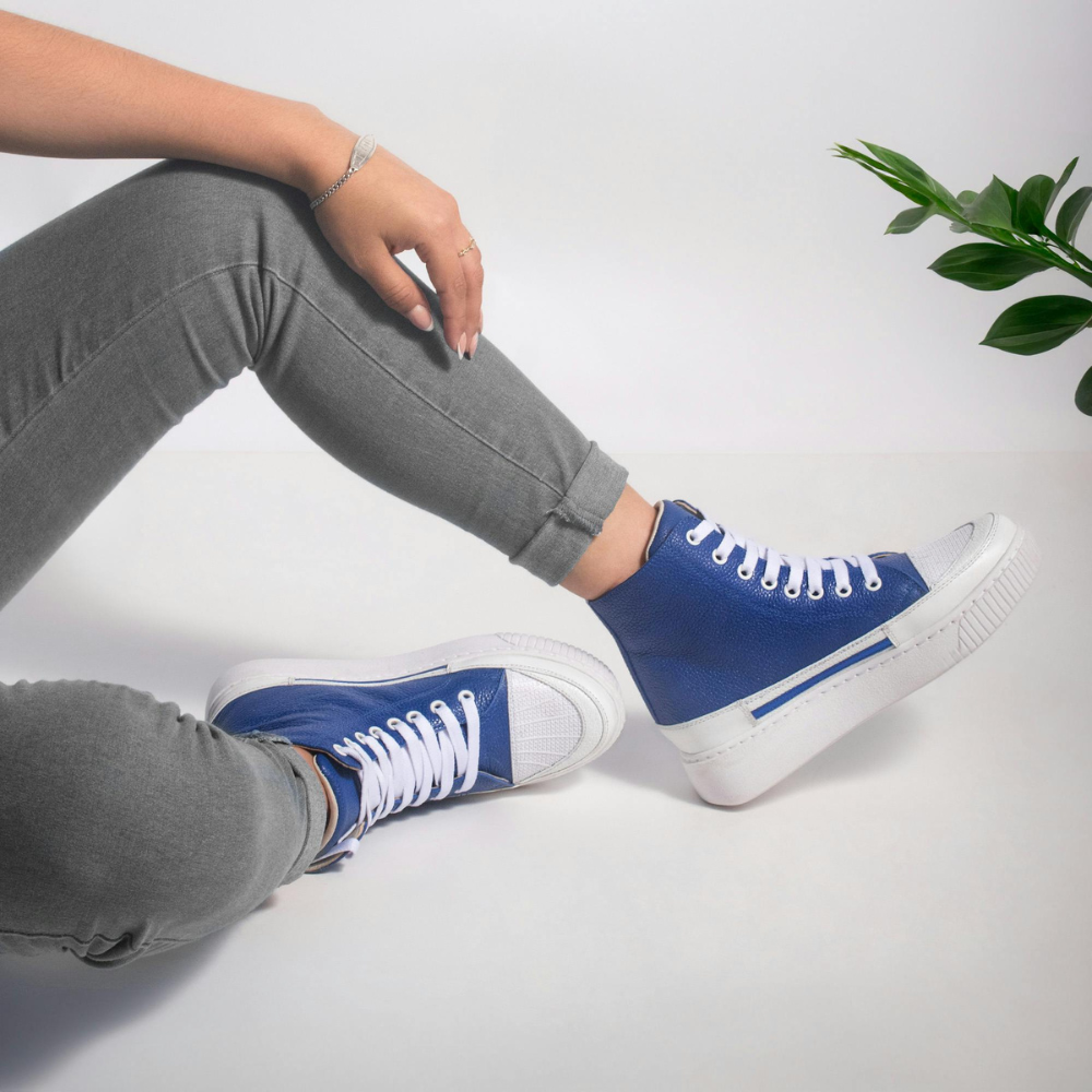 Person wearing blue high-top sneakers with white soles on a light background